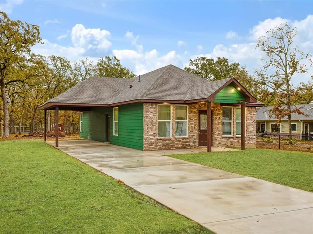 a front view of a house with a garden and trees