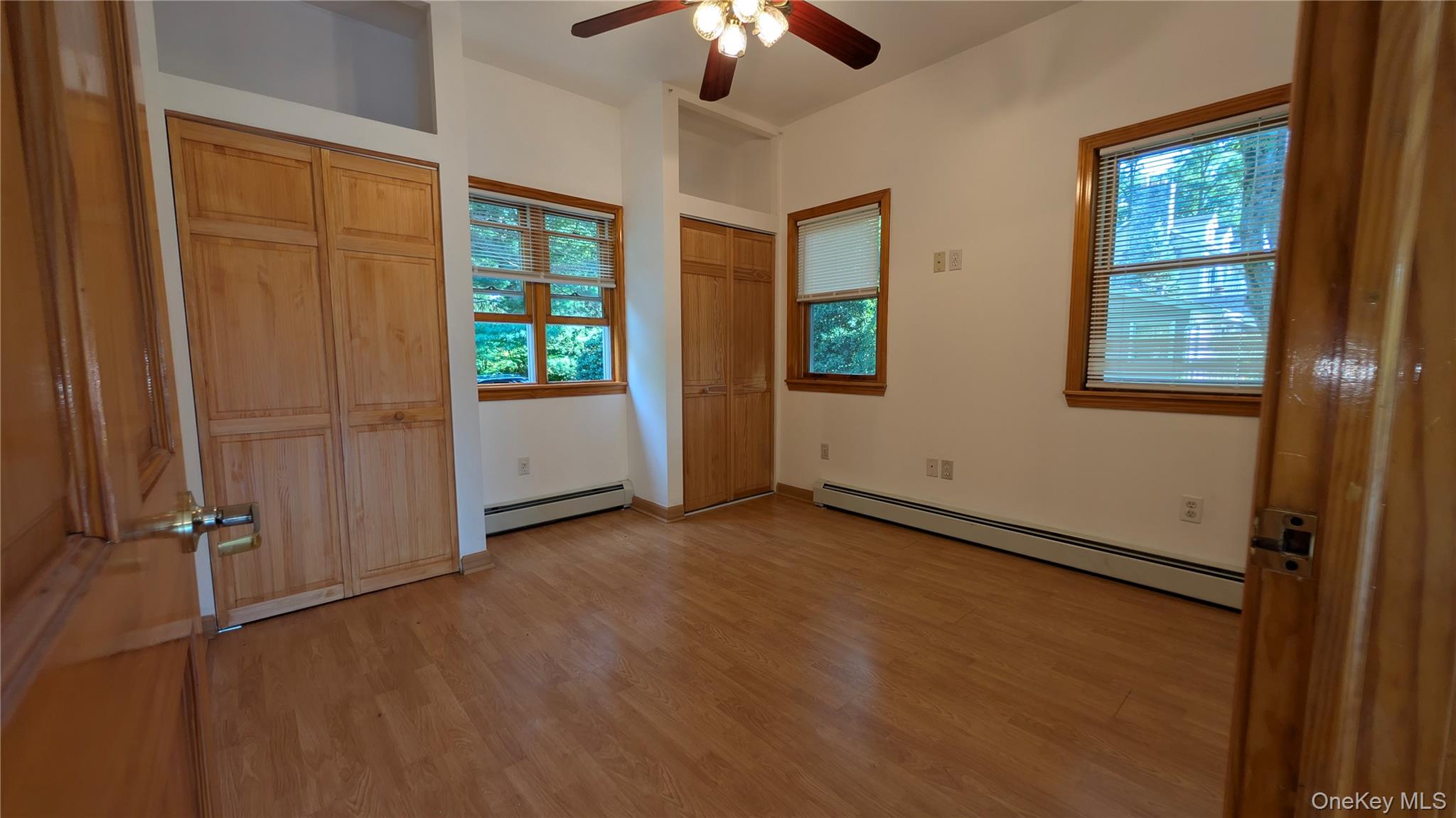 169 Shear Hill Road Mahopac, NY 10541 - Photo 18 of 31 Unfurnished bedroom with two closets, a baseboard radiator, light wood finished floors, and a ceiling fan