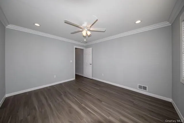 a view of an empty room with wooden floor and a ceiling fan
