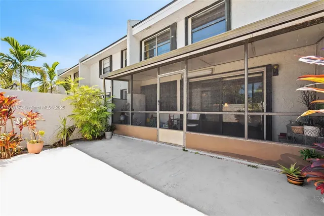 a view of a house with a large window and potted plants