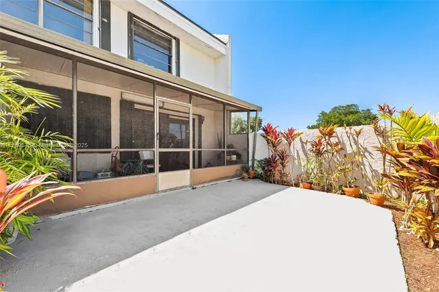 a view of a house with a floor to ceiling window and potted plants