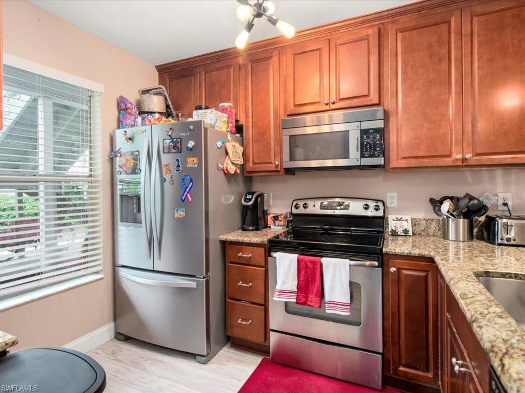 1965 Courtyard Way, Unit E106 Naples, FL 34112 - Photo 3 of 21 a kitchen with stainless steel appliances granite countertop a refrigerator stove and sink