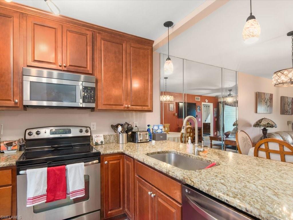 1965 Courtyard Way, Unit E106 Naples, FL 34112 - Photo 4 of 21 a kitchen with stainless steel appliances granite countertop a sink a stove and cabinets