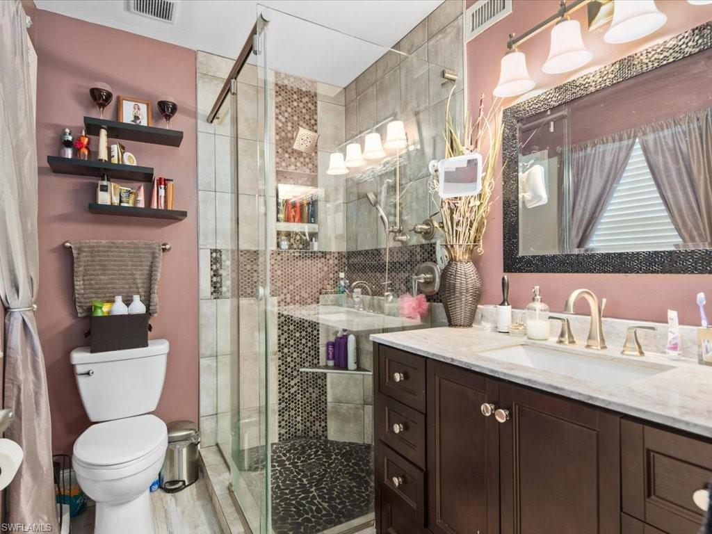 1965 Courtyard Way, Unit E106 Naples, FL 34112 - Photo 10 of 21 a bathroom with a sink toilet vanity and shower