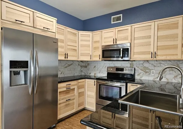 a kitchen with stainless steel appliances granite countertop a refrigerator and a stove top oven
