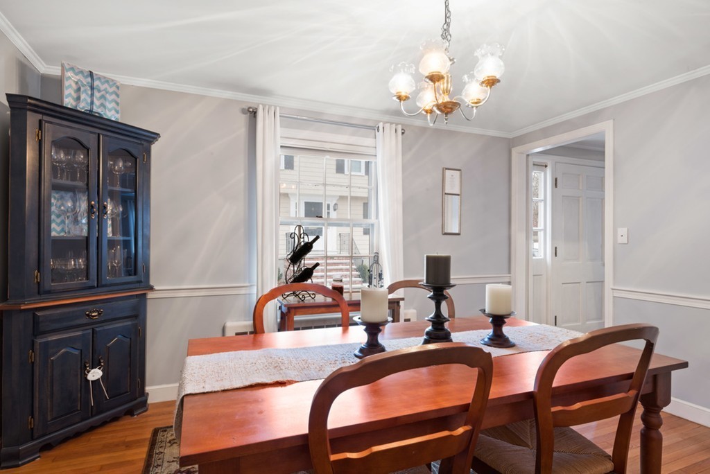 10 Maxwell Road Milton, MA 02186 - Photo 3 of 17 a dining room with wooden floor a chandelier a wooden table and chairs