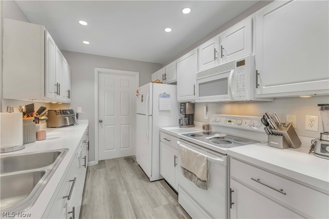 28340 Center Ridge Road, Unit 124 Westlake, OH 44145 - Photo 12 of 37 Kitchen featuring white cabinetry, white appliances, light countertops, light wood-style flooring, and recessed lighting