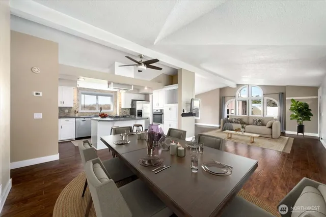 a view of a dining room and livingroom with furniture wooden floor a rug and a chandelier