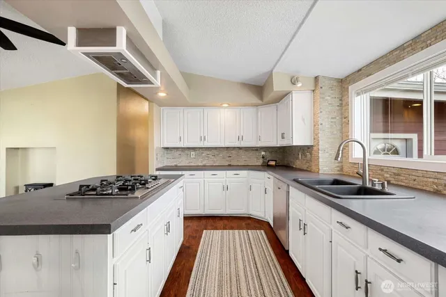 a kitchen with granite countertop a sink stove and cabinets