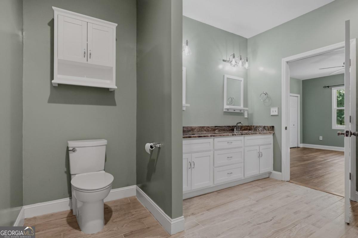 609 Morgan Street Albany, GA 31705 - Photo 23 of 74 a bathroom with a granite countertop toilet a sink and a mirror