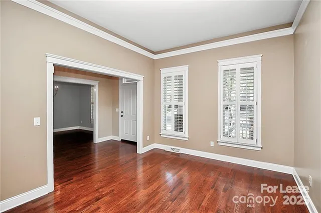 a view of an empty room with window and wooden floor