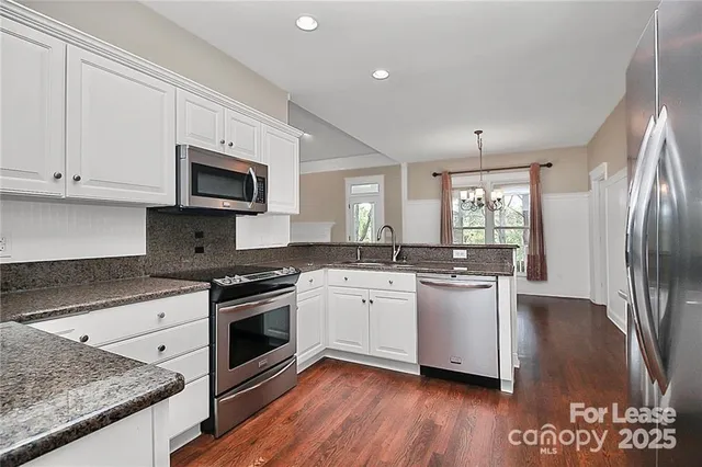 a kitchen with stainless steel appliances granite countertop a stove a sink and a microwave