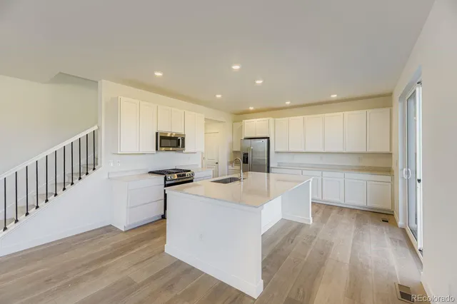 a large kitchen with a center island wooden floor and stainless steel appliances