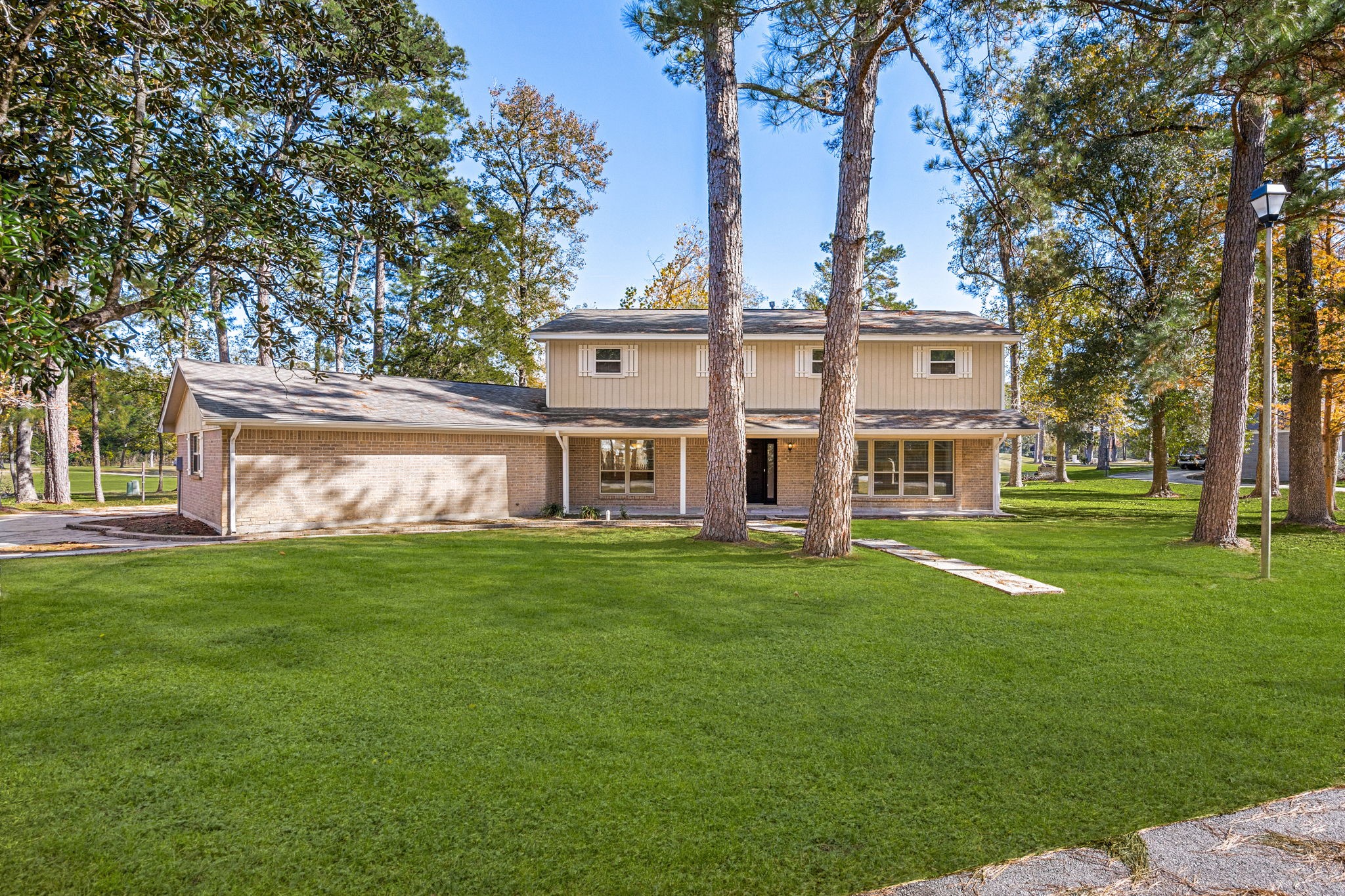 a view of a house with a big yard and large trees