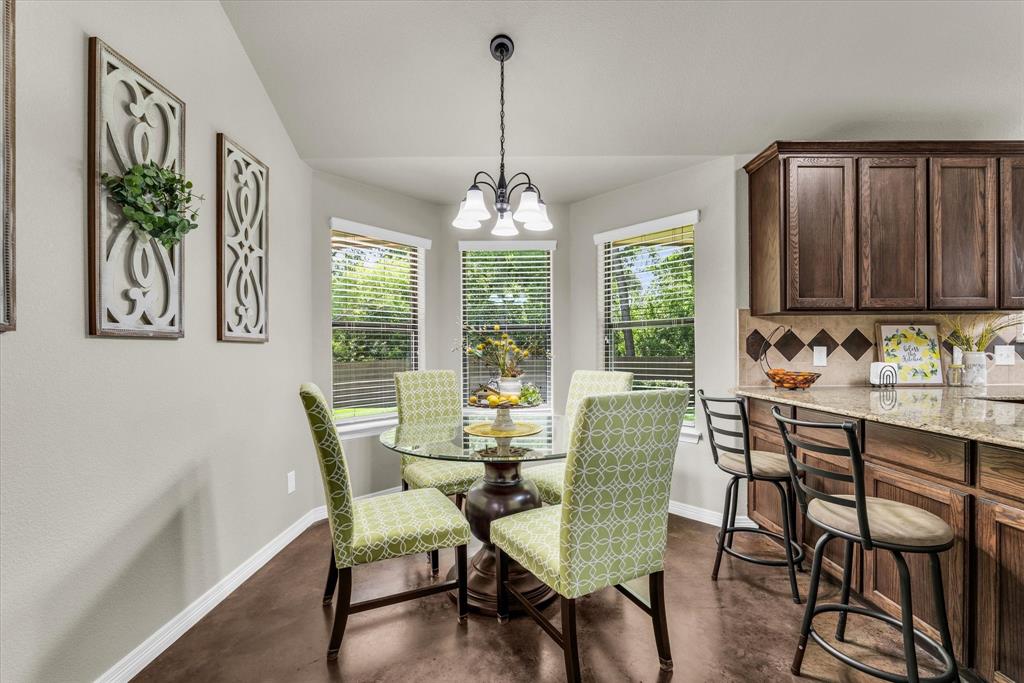 814 Springdale Circle Lorena, TX 76655 - Photo 10 of 37 Breakfast nook with bay windows, overhead lighting, wood-finish flooring, and a kitchen peninsula featuring dark wood cabinetry, a tiled backsplash, and stone countertops