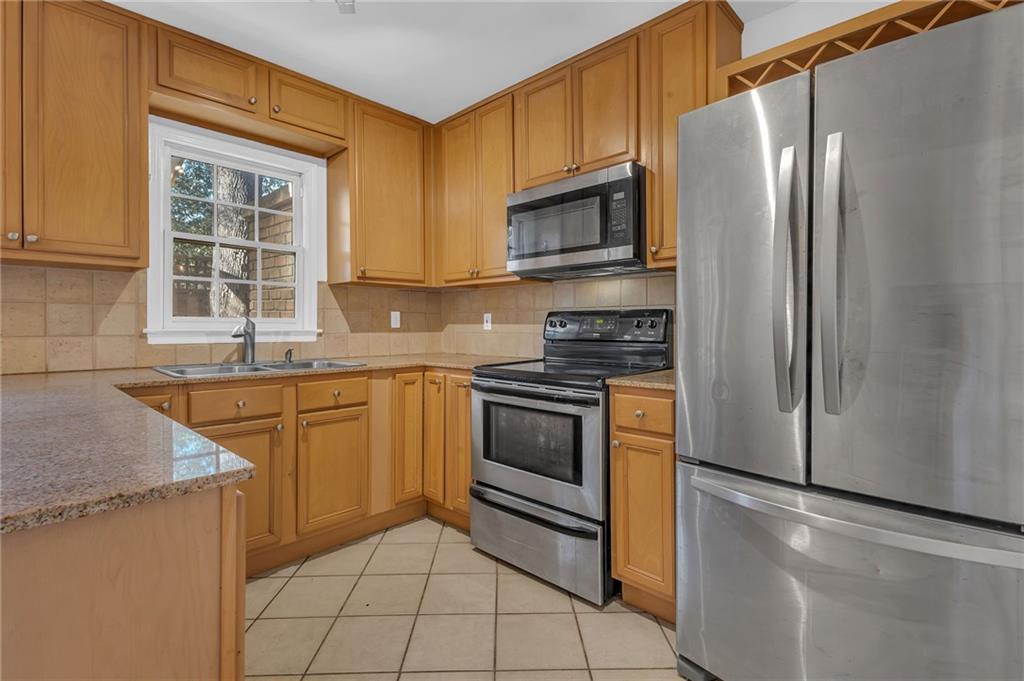 1101 Collier Road Northwest, Unit I2 Atlanta, GA 30318 - Photo 2 of 14 a kitchen with stainless steel appliances granite countertop a refrigerator sink and stove