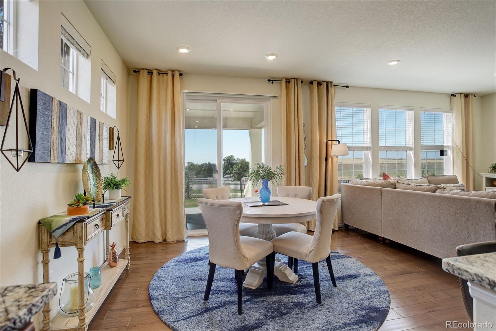 14747 Ulster Loop Thornton, CO 80602 - Photo 9 of 33 a dining room with furniture a rug wooden floor and a rug
