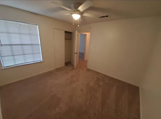 en empty room with windows and ceiling fan