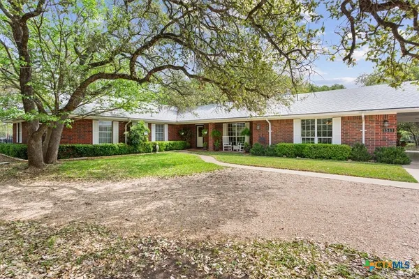 a view of house in front of a big yard with large trees
