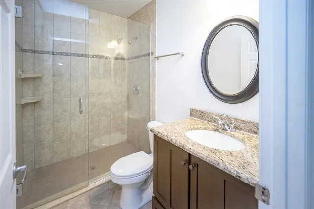 a bathroom with a granite countertop sink toilet a mirror and shower
