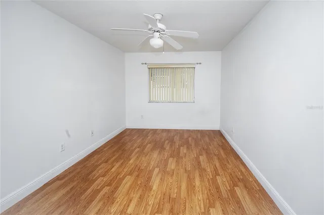 an empty room with a window and a ceiling fan
