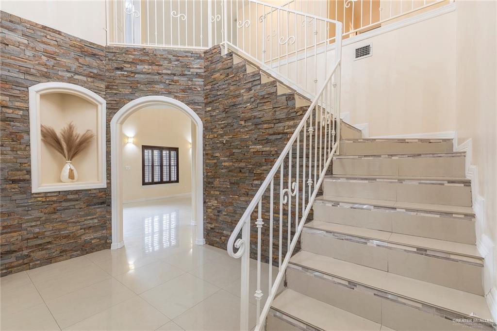 2001 Quail Lane Mission, TX 78572 - Photo 2 of 28 Staircase featuring decorative white metal railings, tile risers, and an adjacent natural stone accent wall