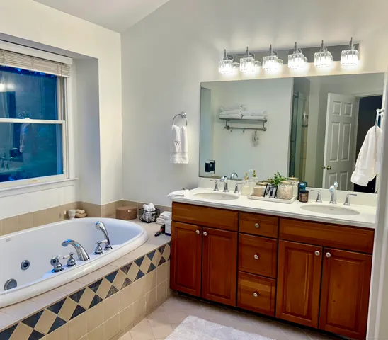 a spacious bathroom with a tub double sink and mirror
