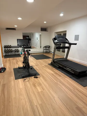 a view of a room with gym equipment and wooden floor