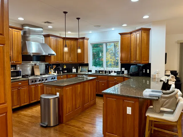 a kitchen with stainless steel appliances kitchen island granite countertop a sink a stove and a refrigerator
