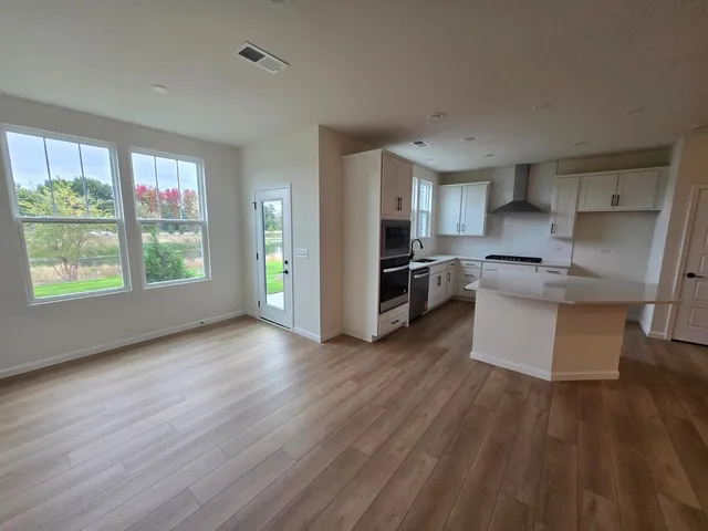 a kitchen with stainless steel appliances granite countertop a refrigerator a stove a sink dishwasher and wooden floor