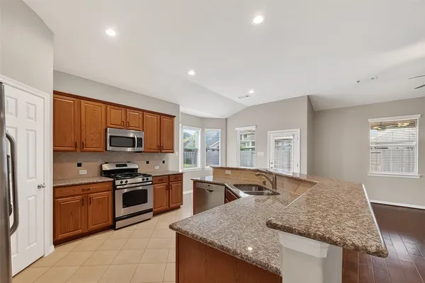 a kitchen with stainless steel appliances granite countertop a stove a sink and a microwave