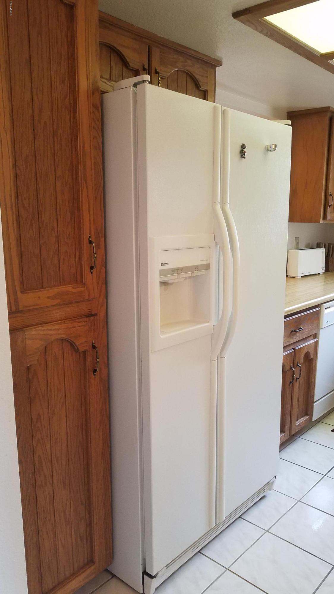 7061 East Broadway Road, Unit 48 Mesa, AZ 85208 - Photo 7 of 41 a white refrigerator freezer and a wooden cabinets