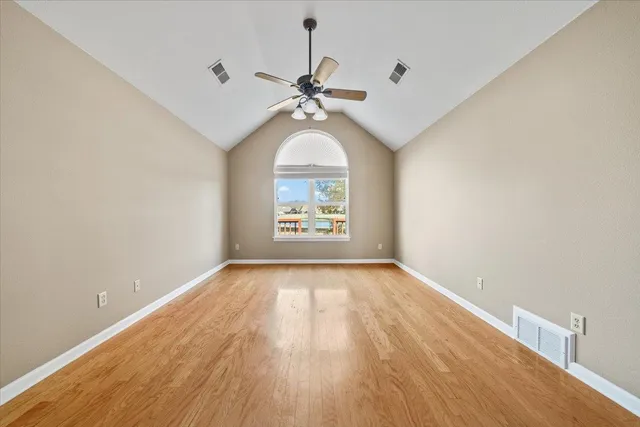 a view of an empty room with window and wooden floor