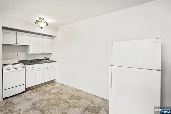 a kitchen with a refrigerator and white cabinets