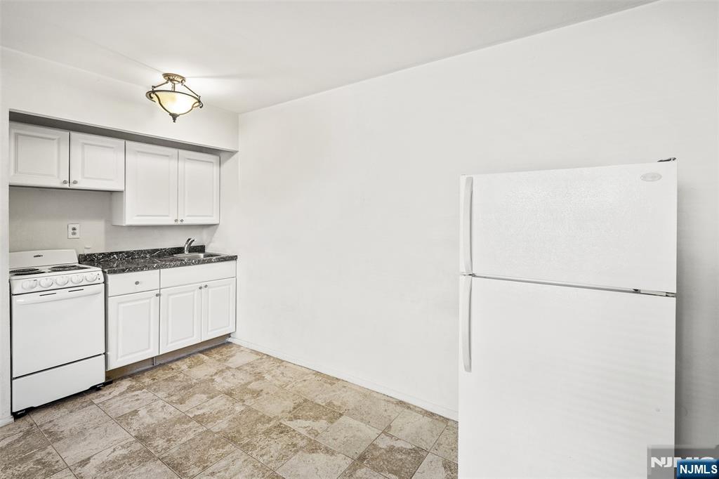 64 Poplar Avenue, Unit A7 Hackensack, NJ 07601 - Photo 5 of 10 a kitchen with a refrigerator and white cabinets