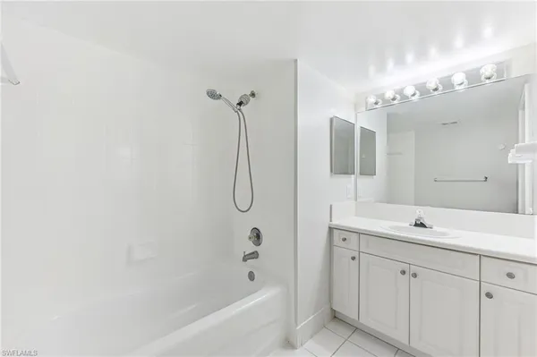 a bathroom with a double vanity sink mirror and bathtub
