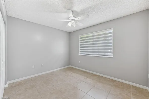 an empty room with a window and a fan