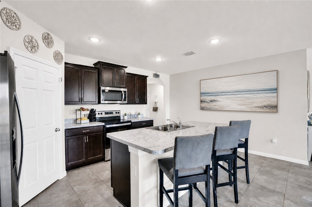 3453 Trinity Circle Fort Pierce, FL 34945 - Photo 7 of 36 a kitchen with stainless steel appliances a table chairs microwave and refrigerator
