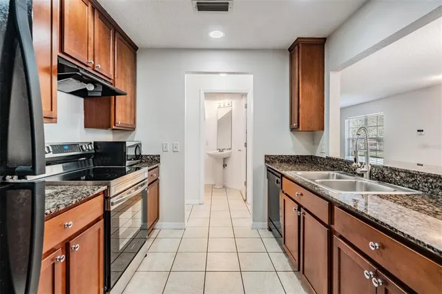 a kitchen with granite countertop a sink stove and cabinets