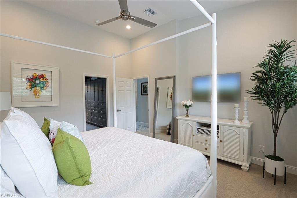 1165 4th Street South, Unit 2 Naples, FL 34102 - Photo 16 of 34 a spacious bedroom with a bed and a chandelier