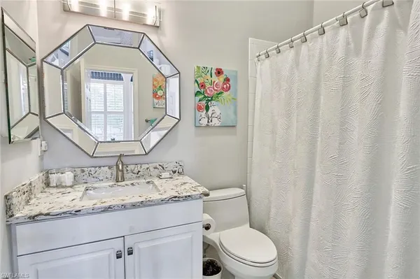 a bathroom with a granite countertop sink a toilet and a mirror