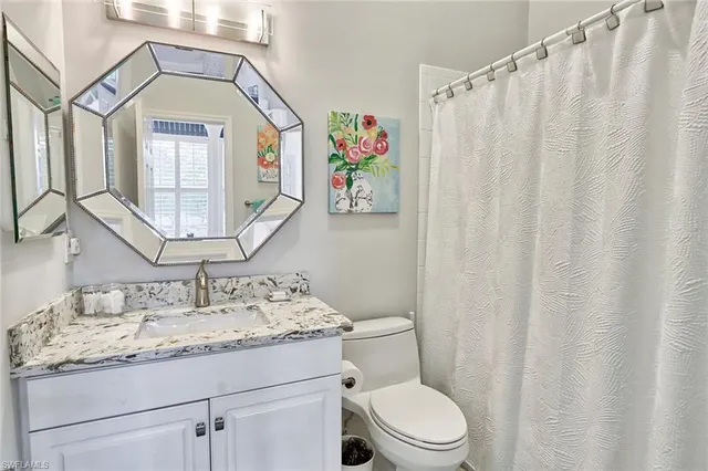a bathroom with a granite countertop sink a toilet and a mirror
