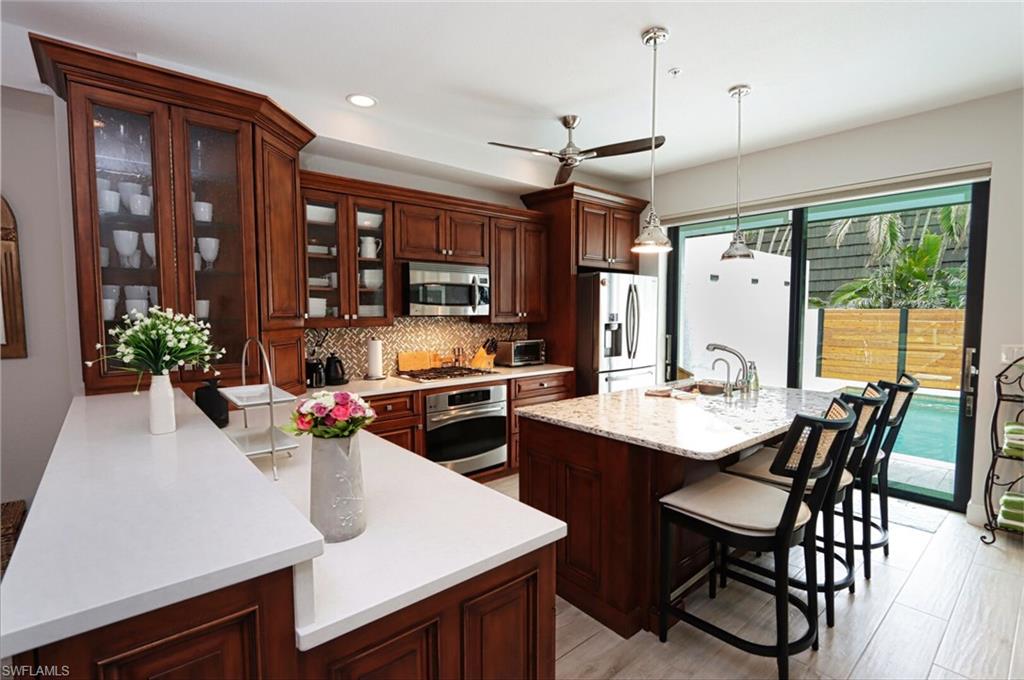 1165 4th Street South, Unit 2 Naples, FL 34102 - Photo 7 of 34 a kitchen with a table chairs stove and cabinets