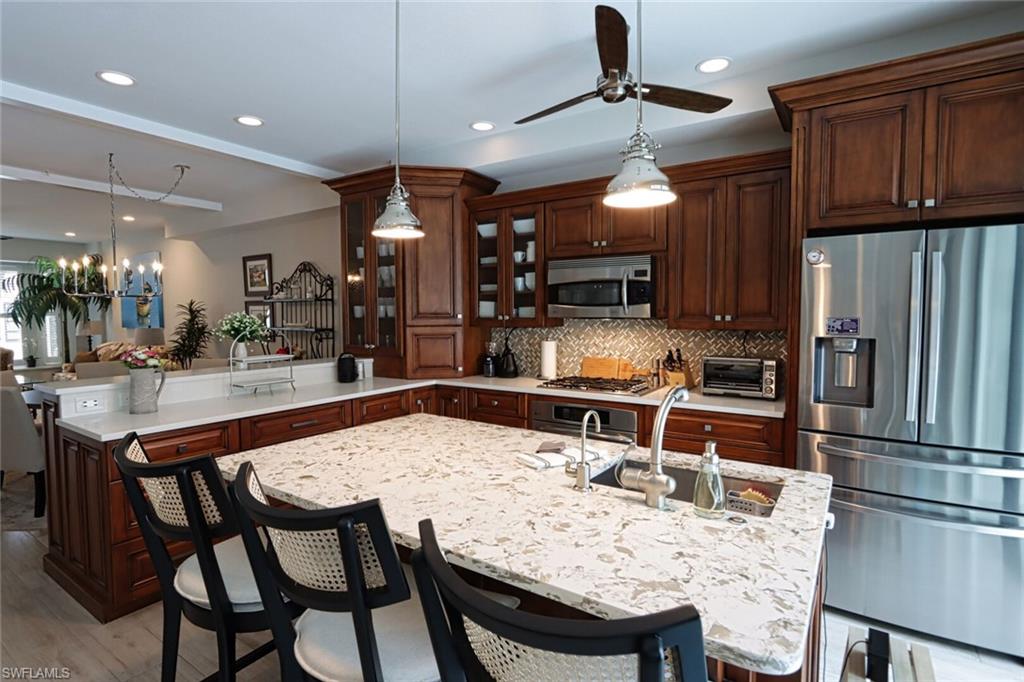 1165 4th Street South, Unit 2 Naples, FL 34102 - Photo 8 of 34 a kitchen with stainless steel appliances kitchen island granite countertop a dining table and chairs