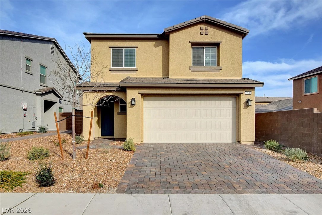 6920 Fossil Rim Street North Las Vegas, NV 89084 - Photo 1 of 9 A welcoming facade features a paver driveway, an integrated garage, and a covered entry.