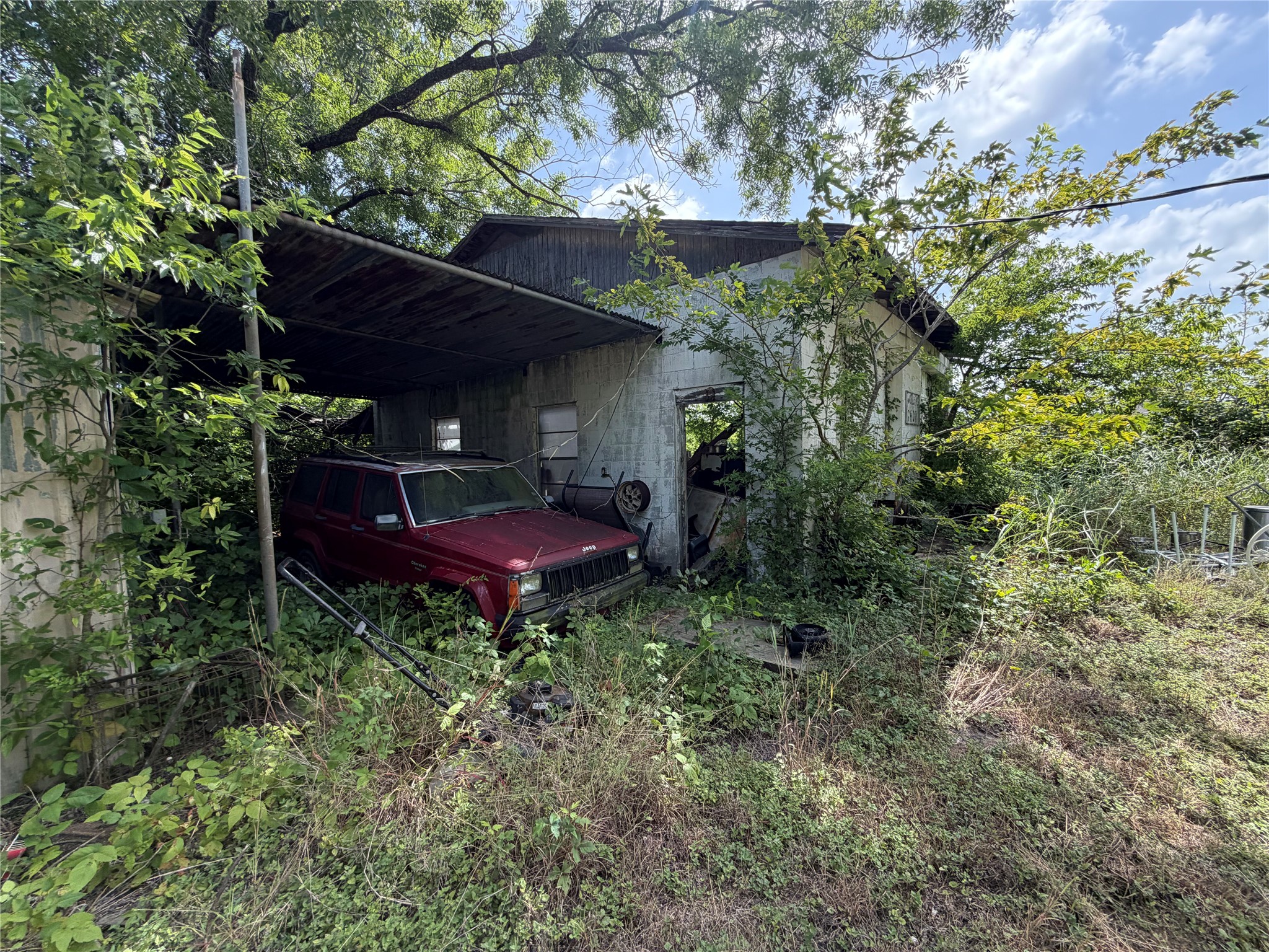 2501 Barnhardt Road Temple, TX 76502 - Photo 21 of 25 A neglected structure with a covered parking area, surrounded by abundant greenery.