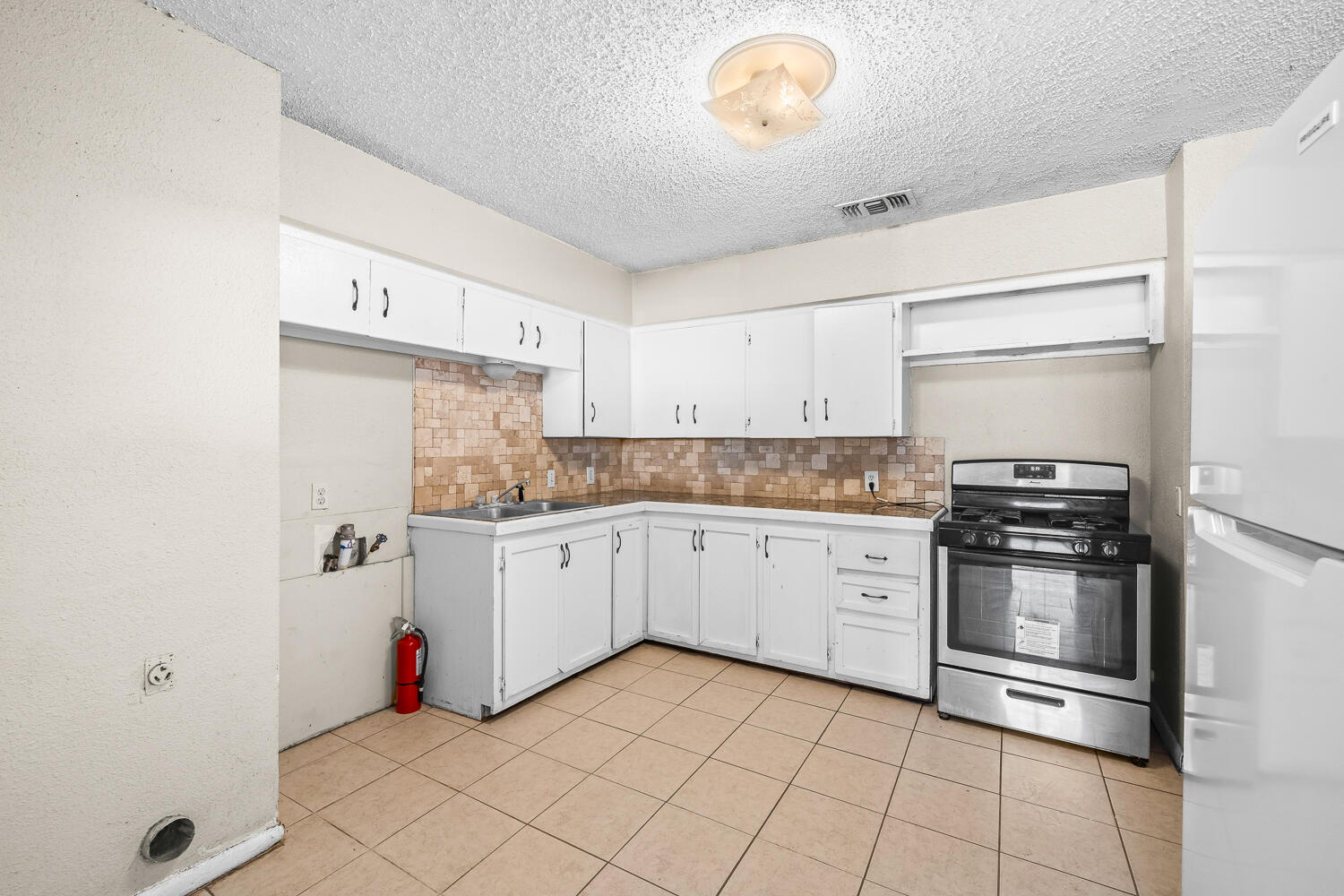 1603 27th Street, Unit B Lubbock, TX 79411 - Photo 5 of 13 a kitchen with granite countertop white cabinets and white appliances