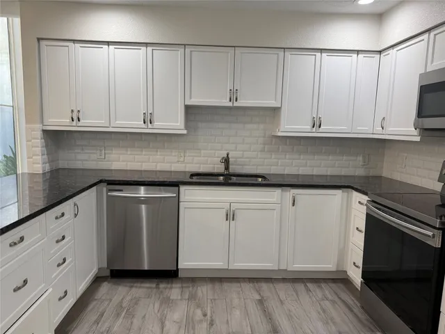 a kitchen with granite countertop white cabinets and stainless steel appliances
