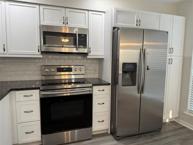 a kitchen with stainless steel appliances white cabinets a stove and a refrigerator