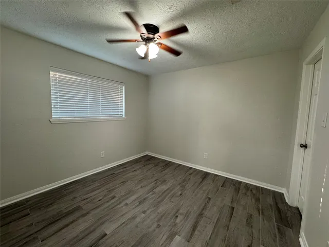 an empty room with wooden floor chandelier fan and windows